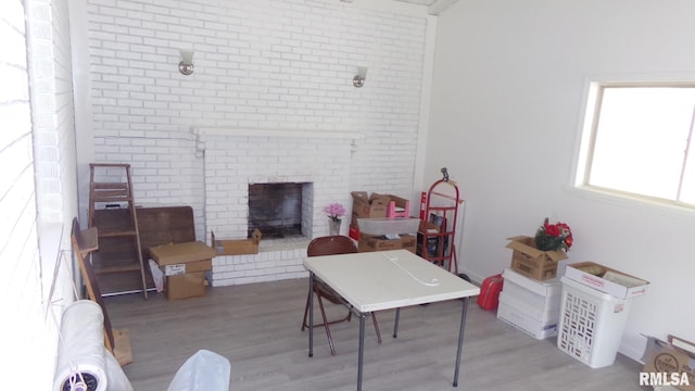 living room featuring a brick fireplace and light wood-type flooring