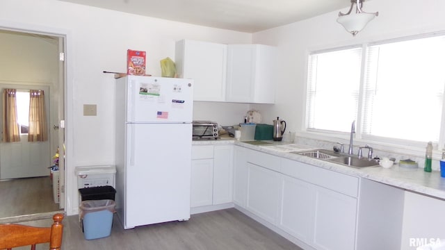 kitchen featuring light hardwood / wood-style floors, sink, white fridge, and white cabinets