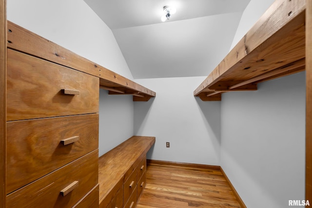 spacious closet with light hardwood / wood-style floors and lofted ceiling