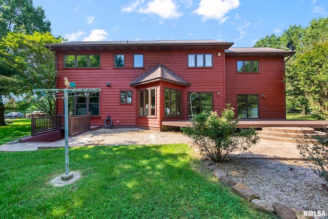 back of house with a patio and a lawn