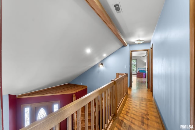 hallway featuring a wealth of natural light, hardwood / wood-style flooring, and vaulted ceiling with beams