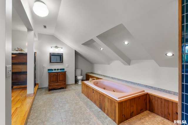 bathroom featuring vaulted ceiling, a bathing tub, hardwood / wood-style flooring, toilet, and vanity