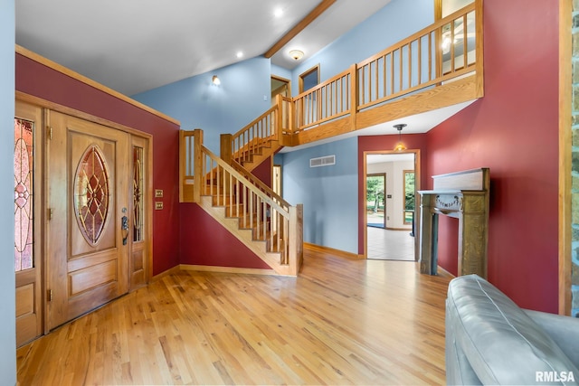 foyer entrance with light wood-type flooring and vaulted ceiling with beams