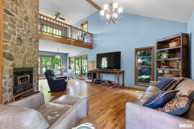 living room with high vaulted ceiling, a fireplace, wood-type flooring, and ceiling fan with notable chandelier