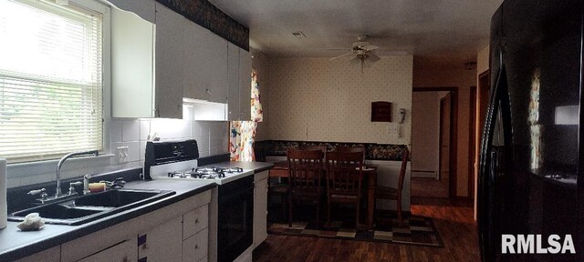 108 N Spencer St, Mounds, IL 62964 - kitchen with gas range oven, freestanding refrigerator, dark wood-style floors, a sink, and white cabinetry