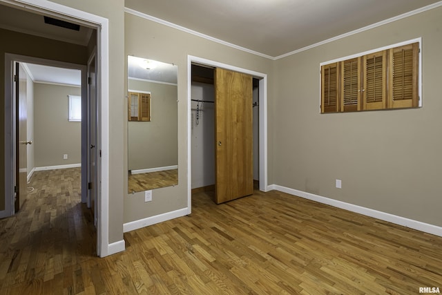 unfurnished bedroom featuring hardwood / wood-style flooring, ornamental molding, and a closet