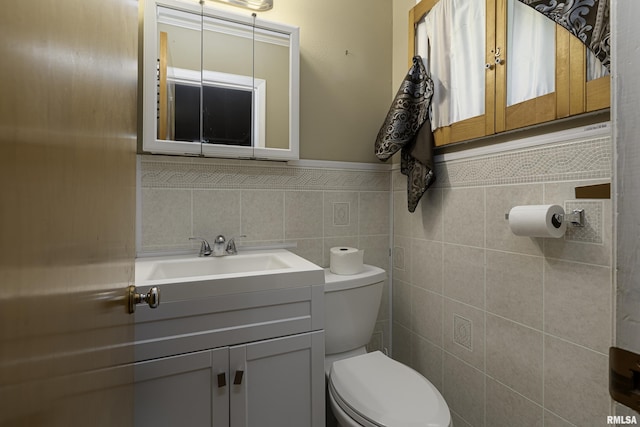 bathroom with vanity, toilet, and tile walls