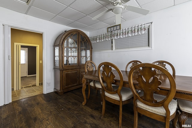 dining area featuring a drop ceiling, dark hardwood / wood-style flooring, and ceiling fan