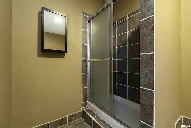 bathroom with tiled shower and tile patterned floors