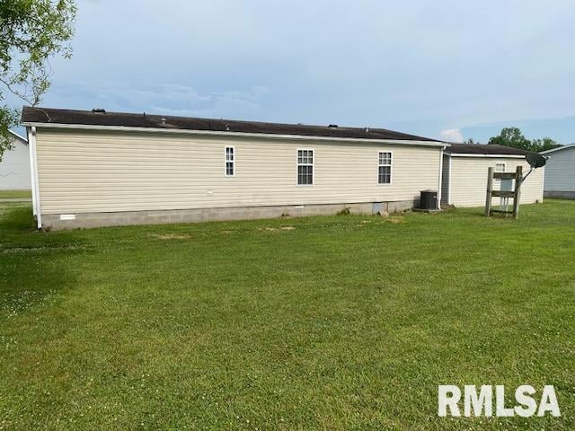 rear view of property with central AC and a yard