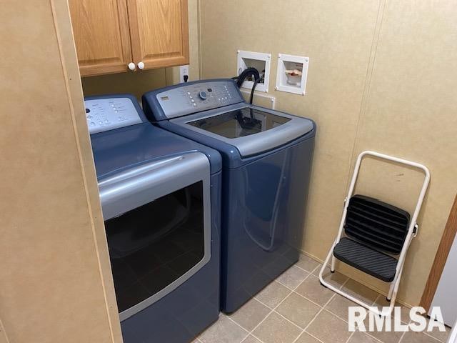 washroom with washing machine and clothes dryer, washer hookup, cabinets, and light tile floors