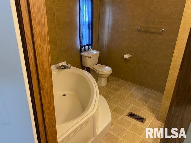 bathroom featuring tile floors, a tub, and toilet