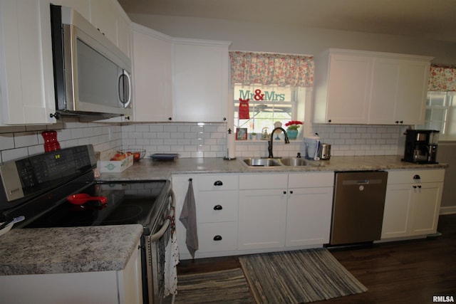 kitchen featuring decorative backsplash, white cabinetry, stainless steel appliances, and a sink