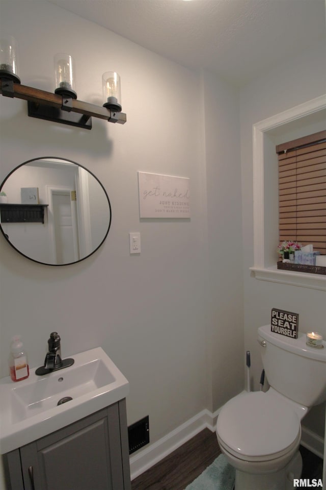 half bath featuring toilet, baseboards, wood finished floors, and vanity