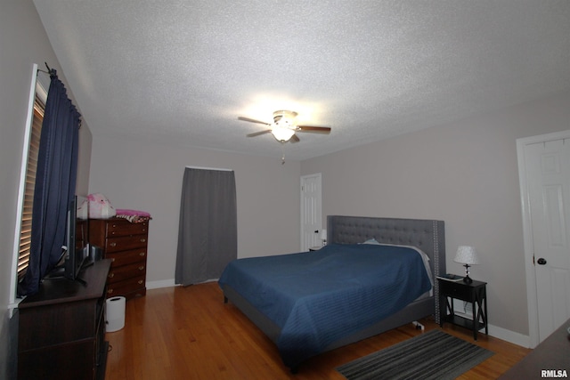 bedroom featuring a textured ceiling, baseboards, and wood finished floors