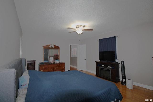 bedroom with a textured ceiling, ceiling fan, light wood-style flooring, and baseboards