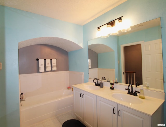 bathroom featuring double vanity, a garden tub, tile patterned flooring, and a sink