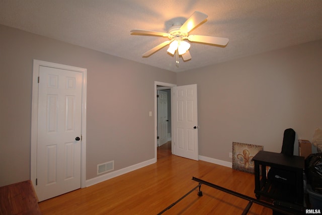 bedroom featuring visible vents, a ceiling fan, a textured ceiling, wood finished floors, and baseboards