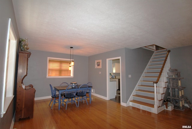 dining room featuring stairs, a textured ceiling, baseboards, and wood finished floors