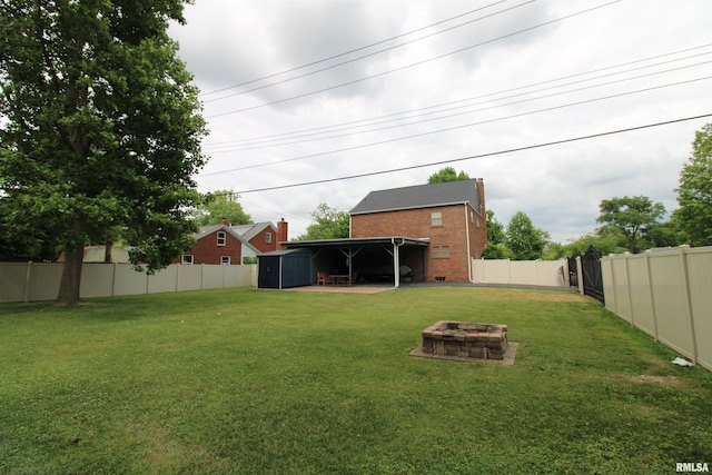 view of yard with a fenced backyard, an outdoor structure, a fire pit, and a shed