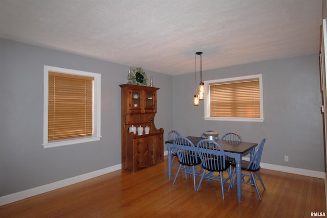 dining room with a textured ceiling, wood finished floors, and baseboards