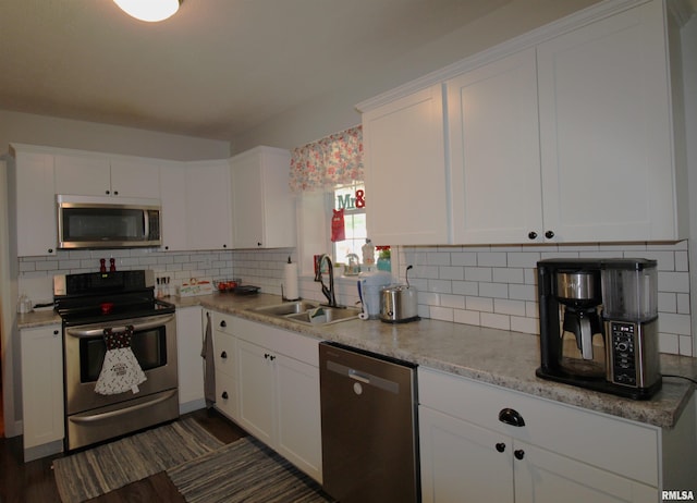 kitchen with stainless steel appliances, white cabinetry, a sink, and backsplash