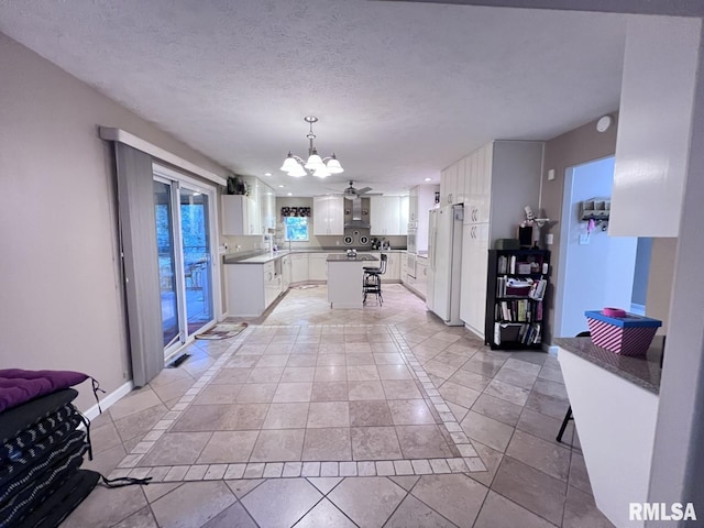 kitchen featuring white cabinetry, white fridge with ice dispenser, hanging light fixtures, a textured ceiling, and light tile patterned flooring