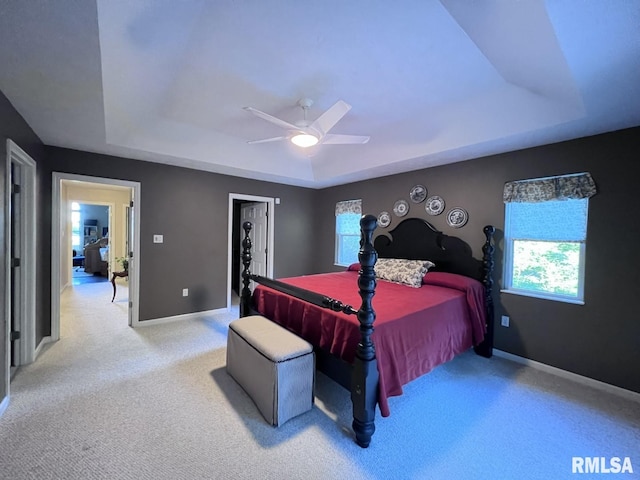 bedroom with a tray ceiling, ceiling fan, and light colored carpet