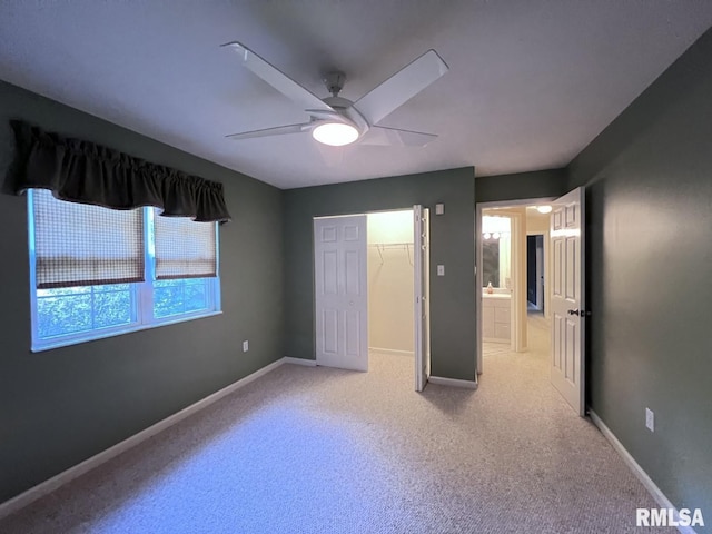 unfurnished bedroom with a walk in closet, a closet, and ceiling fan