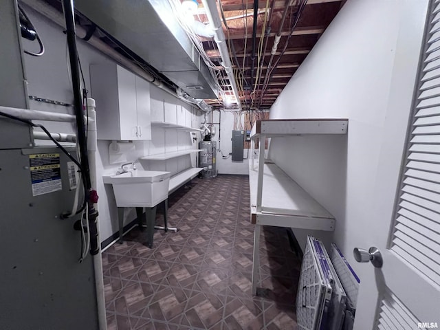 basement featuring electric panel, water heater, and sink