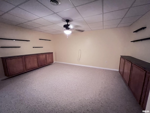 basement with light carpet, a paneled ceiling, and ceiling fan