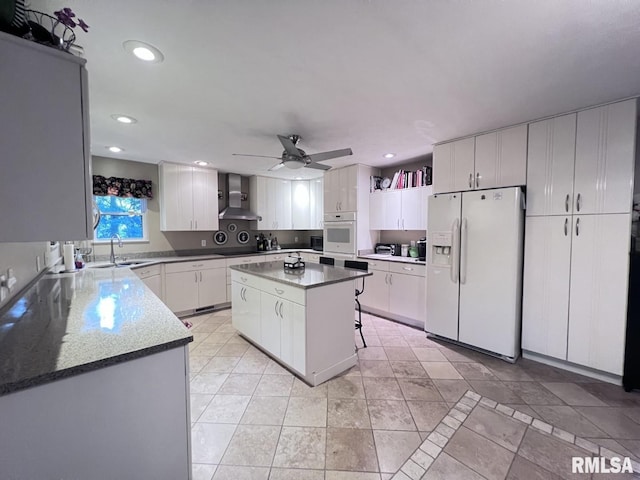 kitchen with white cabinetry, a center island, wall chimney exhaust hood, and white appliances