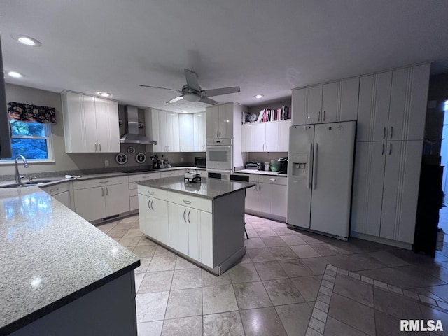 kitchen featuring wall chimney exhaust hood, sink, a center island, white cabinetry, and white fridge with ice dispenser