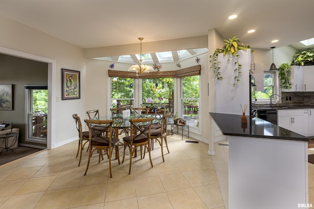 tiled dining area featuring a skylight, sink, and an inviting chandelier