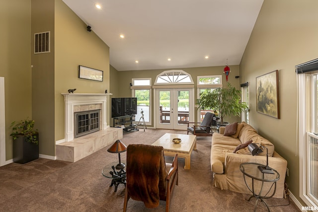 carpeted living room with french doors, high vaulted ceiling, and a tiled fireplace