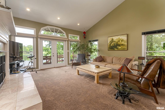 carpeted living room with a tile fireplace, french doors, and high vaulted ceiling