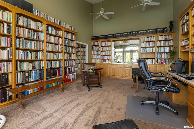 carpeted home office featuring ceiling fan and a high ceiling