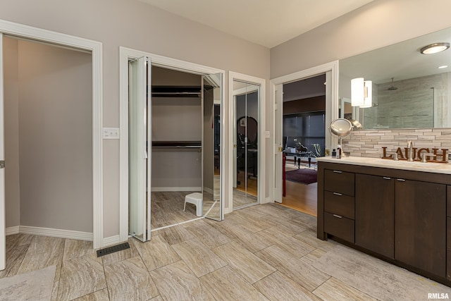 bathroom featuring vanity, walk in shower, and backsplash