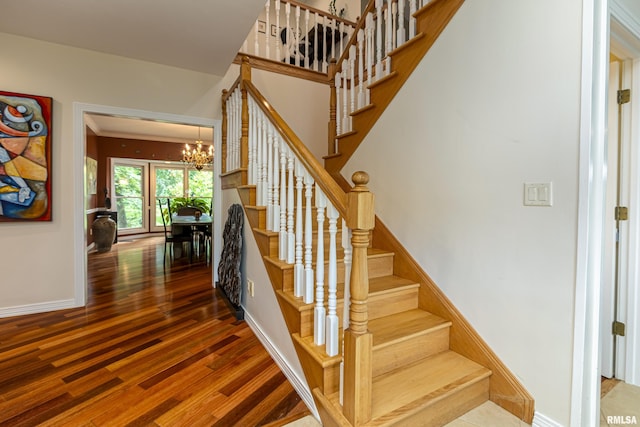 stairs with hardwood / wood-style floors and an inviting chandelier