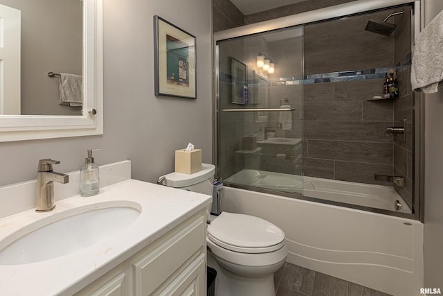 full bathroom featuring combined bath / shower with glass door, vanity, and toilet