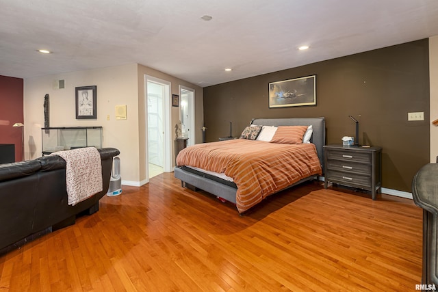 bedroom with light wood-type flooring and ensuite bathroom