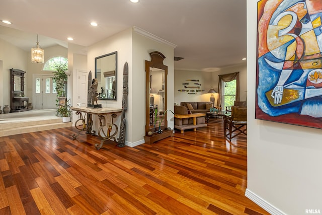 corridor with hardwood / wood-style floors, a notable chandelier, and crown molding