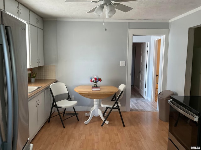 dining area with light hardwood / wood-style floors, a textured ceiling, crown molding, sink, and ceiling fan