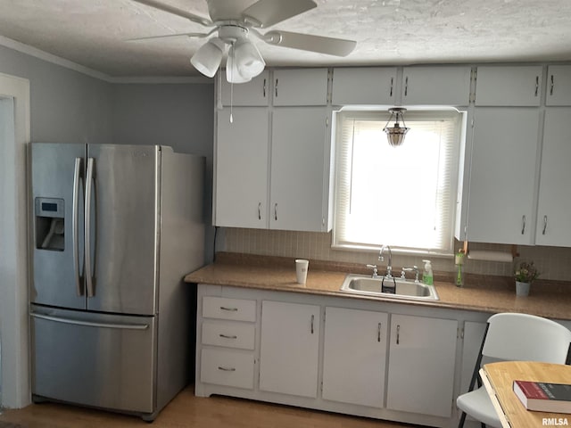 kitchen with white cabinetry, sink, stainless steel fridge, and crown molding