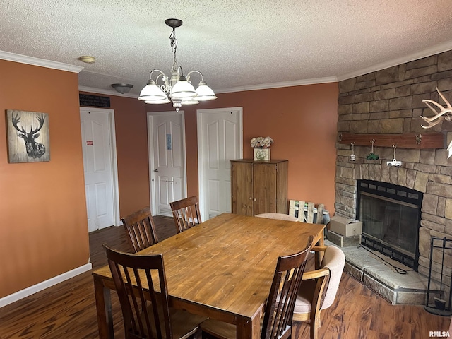 dining space featuring a textured ceiling, a stone fireplace, ornamental molding, and wood finished floors