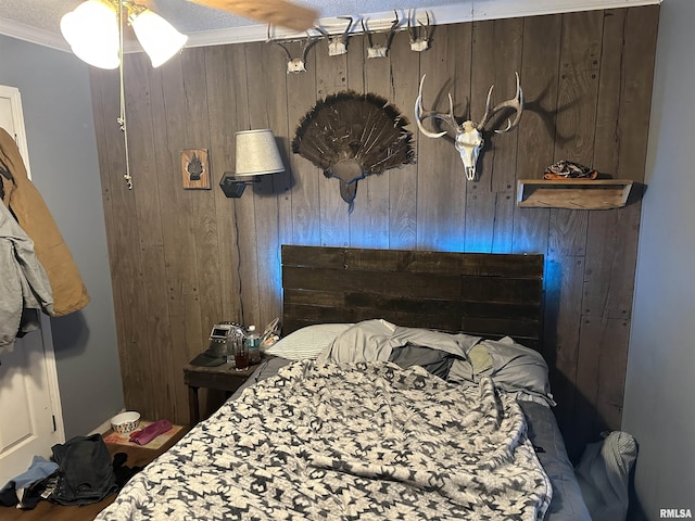 bedroom with ornamental molding, wood walls, and a textured ceiling