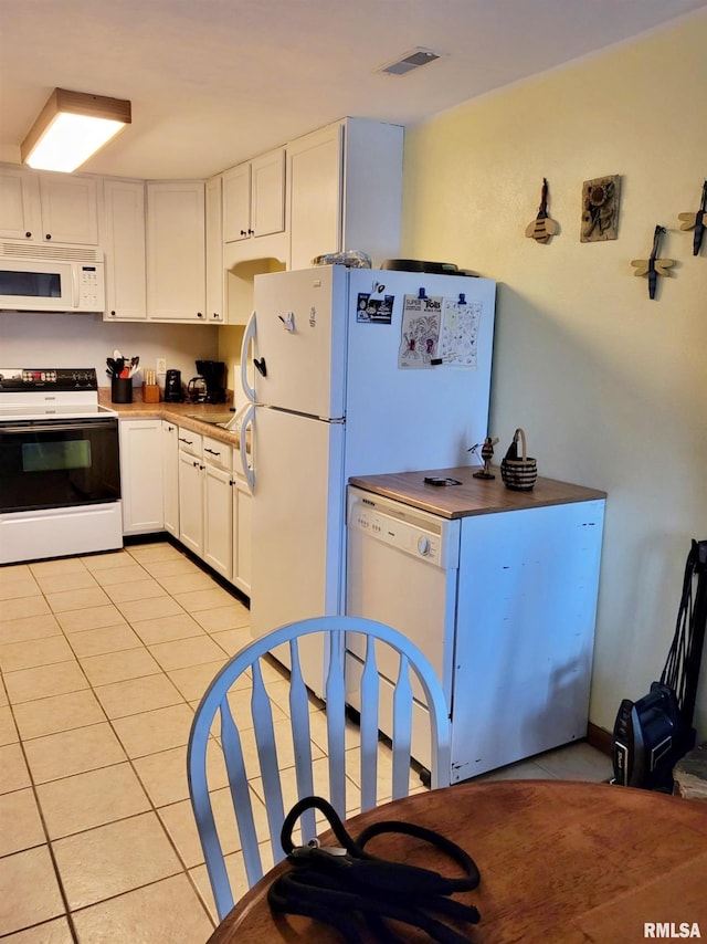 kitchen featuring white cabinets, light tile patterned flooring, and white appliances