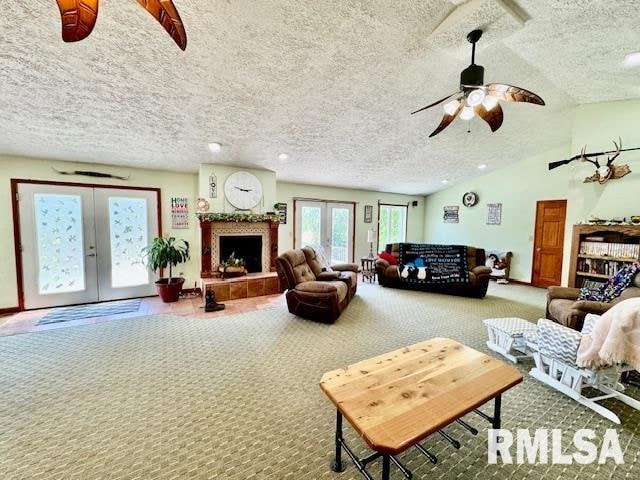 carpeted living room featuring a tiled fireplace, french doors, and a textured ceiling