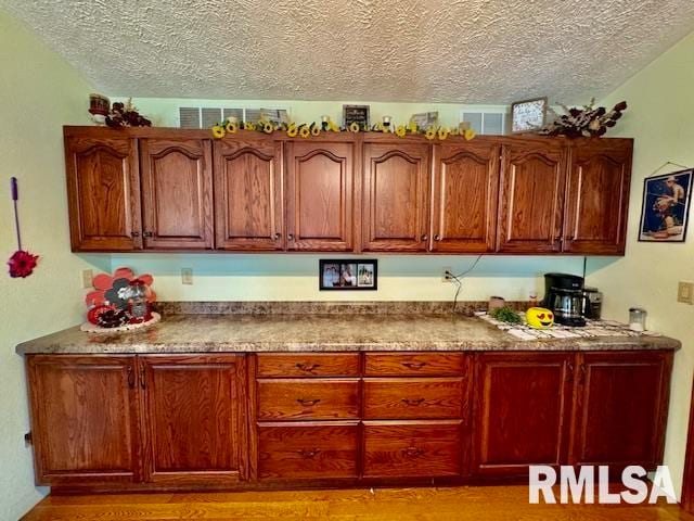 kitchen featuring light stone countertops, light wood-type flooring, and a textured ceiling