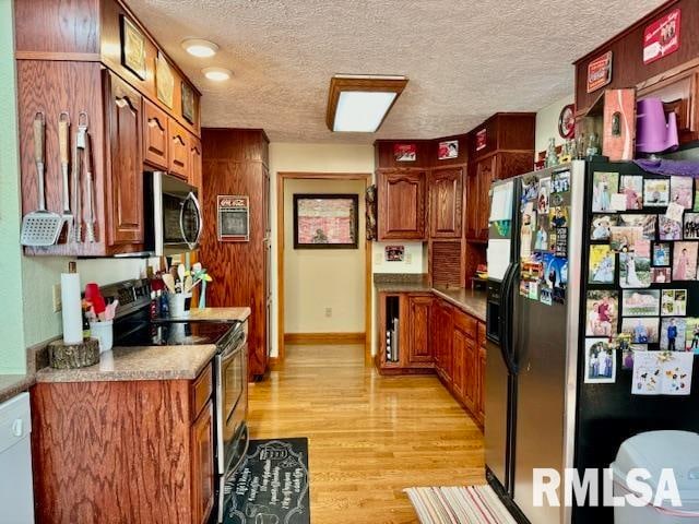 kitchen featuring stainless steel appliances, light hardwood / wood-style floors, and a textured ceiling